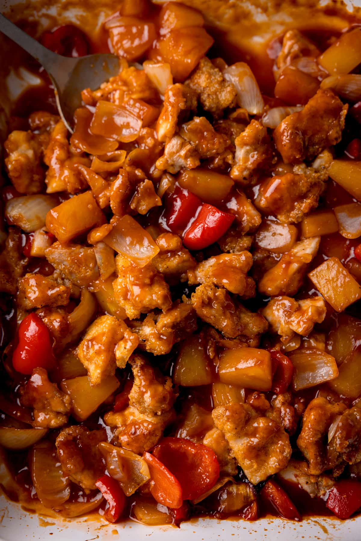 Close up overhead picture of baked sweet and sour chicken in a white baking dish.