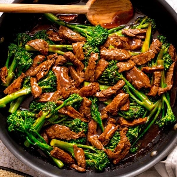 beef and broccoli stir fry in a pan with a wooden spoon