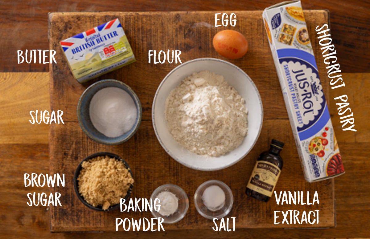 Labelled ingredients for a blueberry crumble pie on a wooden board.