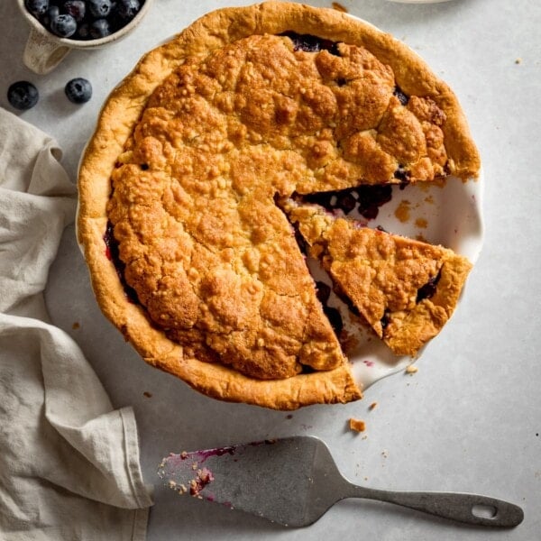 Overhead picture of a blueberry crumble pie with a piece taken out.