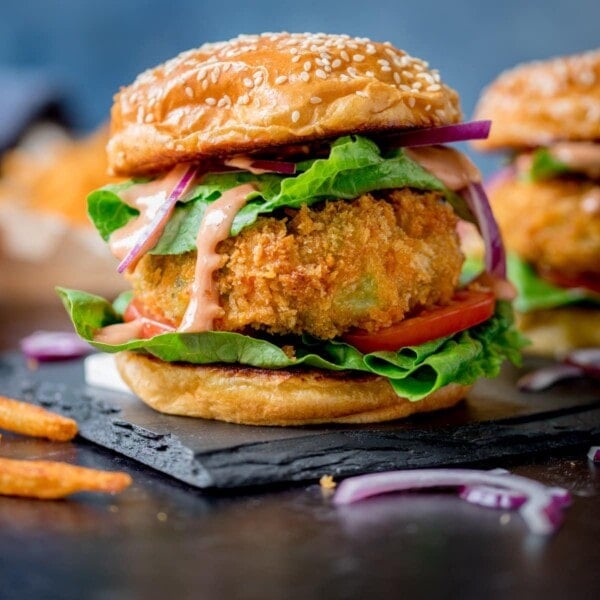 Cheesy Veggie Burger with lettuce on sesame seed bun on blue background