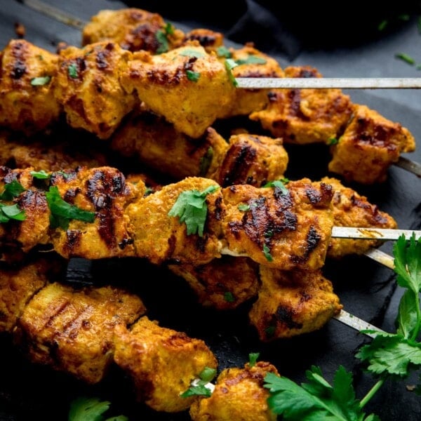 chicken tikka skewers on a dark background