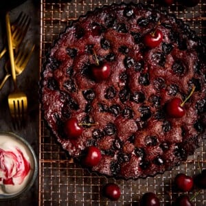 Chocolate Cherry Cake on a wire rack with cherries scattered around.