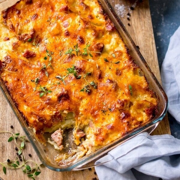 Scalloped potatoes with ham in a dish, with a scoop taken out