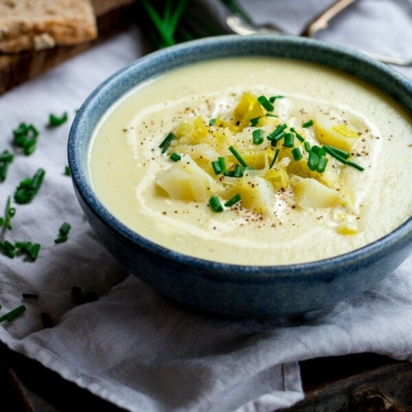 leek and potato soup in a blue bowl, topped with potatoes and chives