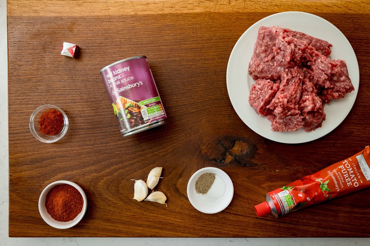 Ingredients for minced beef filling for mini burritos on a wooden board.