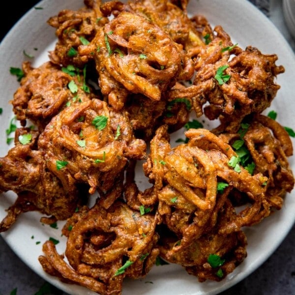 Onion bhajis on a white plate, sprinkled with coriander.