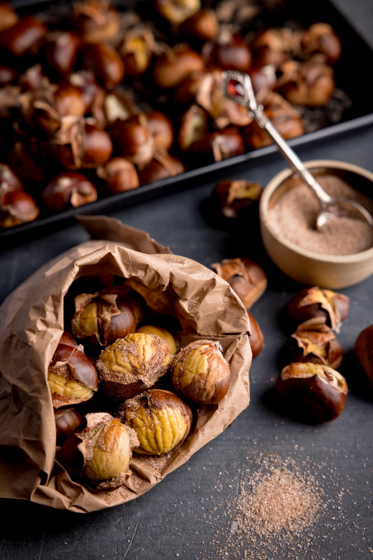 Close up of some roasted chestnuts sprinkled with cinnamon sugar in a brown paper bag.