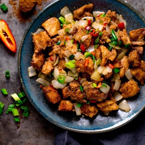 salt and pepper chicken on a dark blue plate