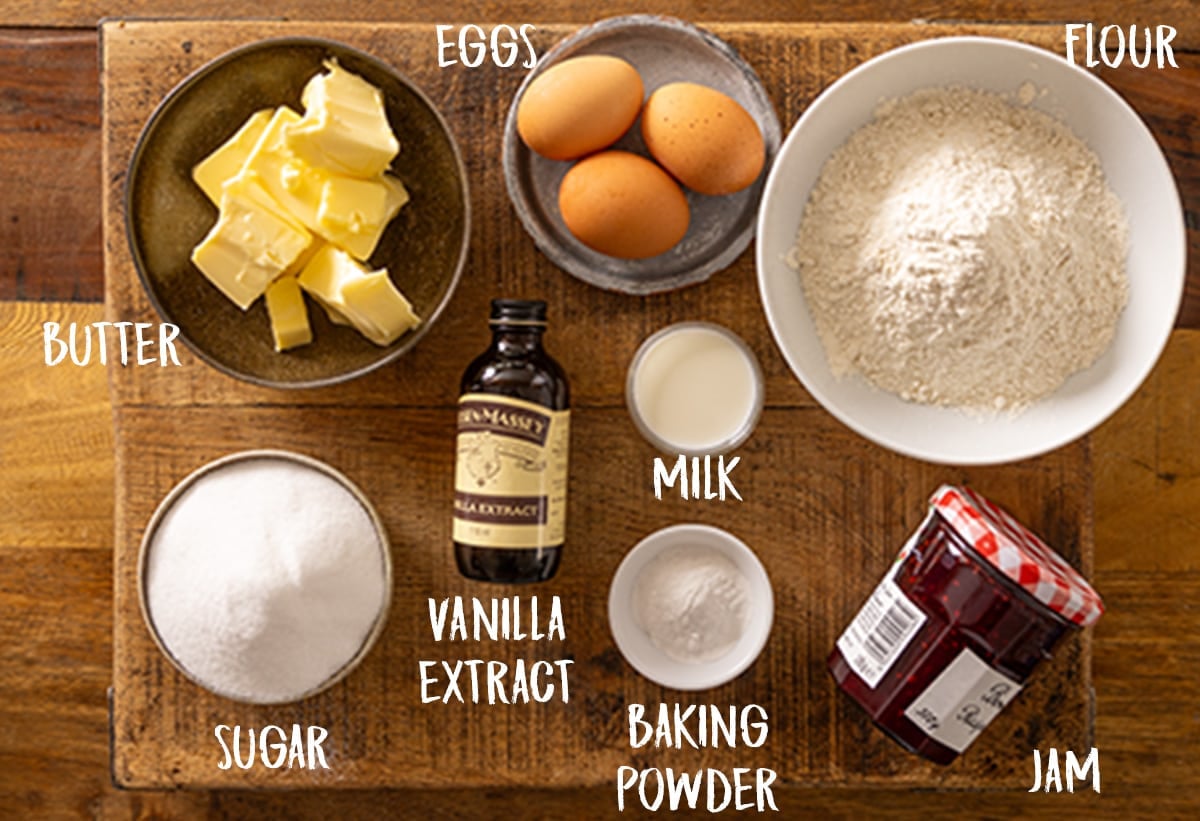 Overhead view of individually labeled ingredients for a steamed jam sponge pudding on a wooden board.