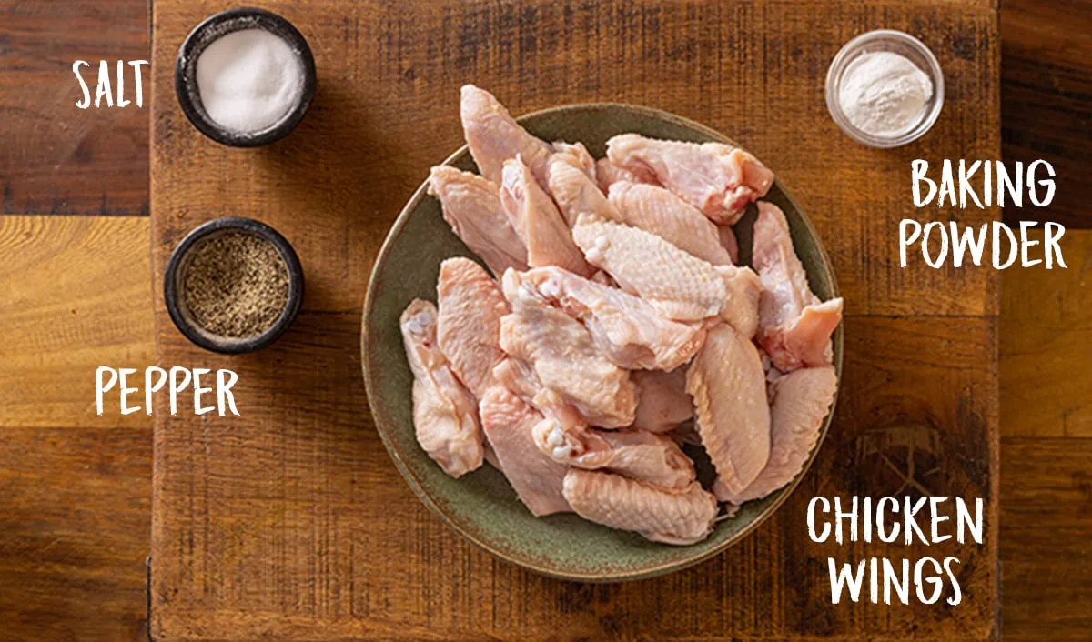 Ingredients for air fryer chicken wings on a wooden board.