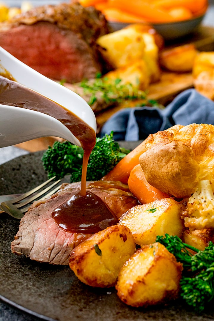 Gravy being poured onto a roast beef dinner