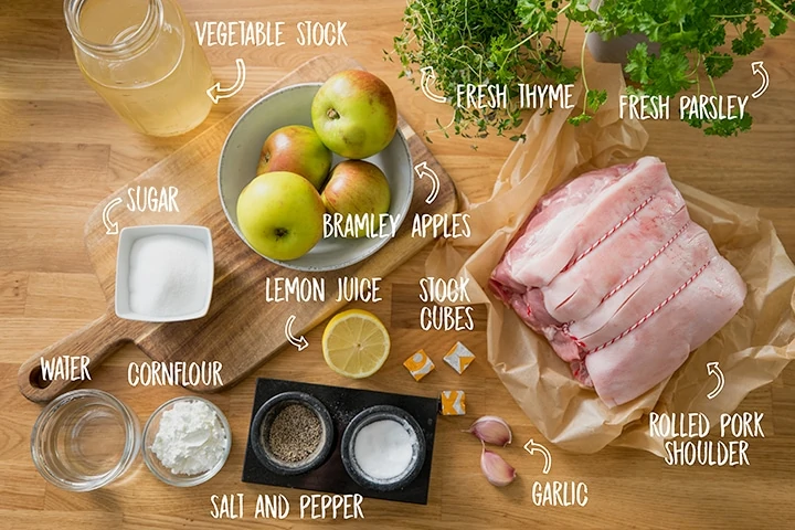 Ingredients for roast pork with apple sauce and gravy on a wooden table