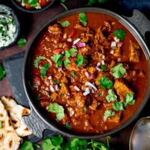 Slow-cooked spicy beef curry in a dish on a dark background